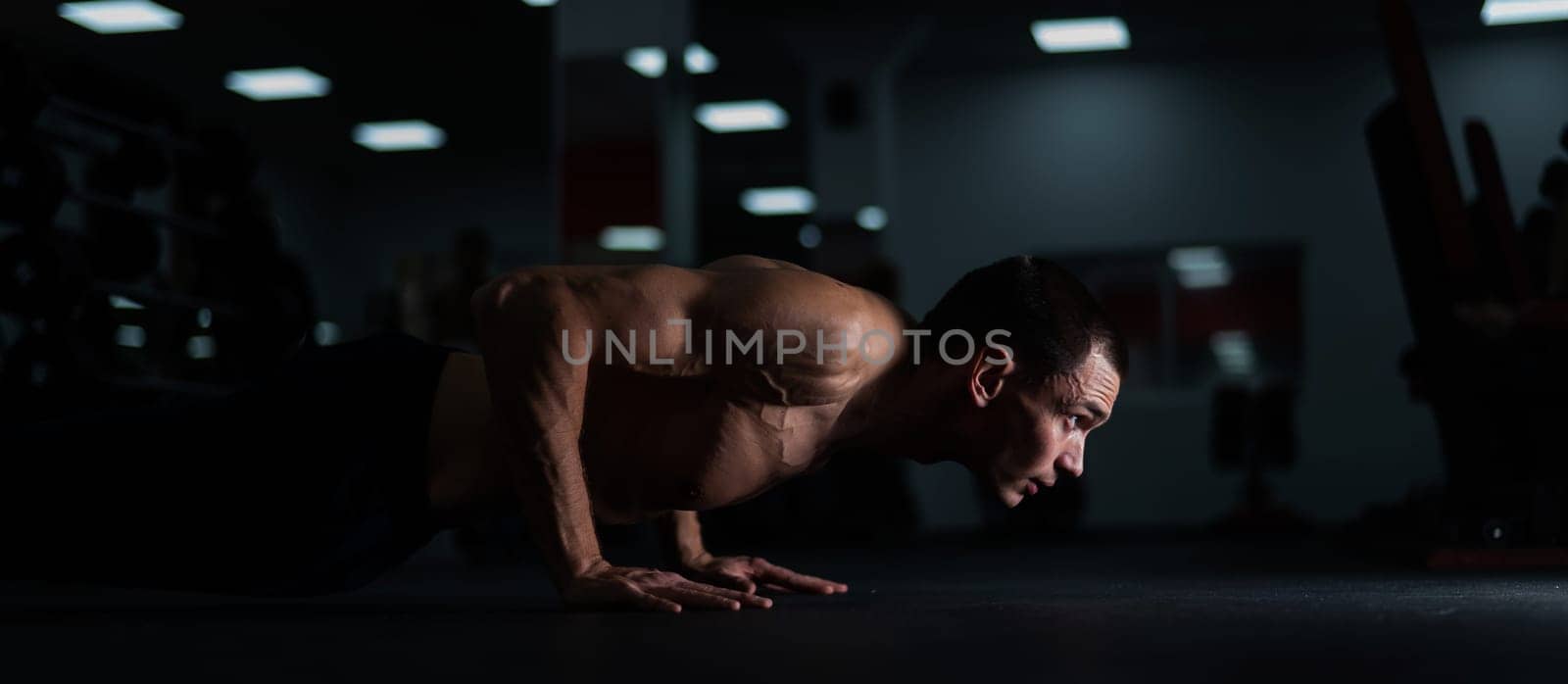 Muscular shirtless man doing push ups in the gym. by mrwed54