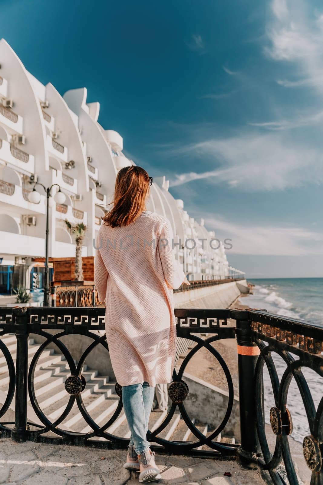 Woman travel sea. Young Happy woman in a long red dress posing on a beach near the sea on background of volcanic rocks, like in Iceland, sharing travel adventure journey