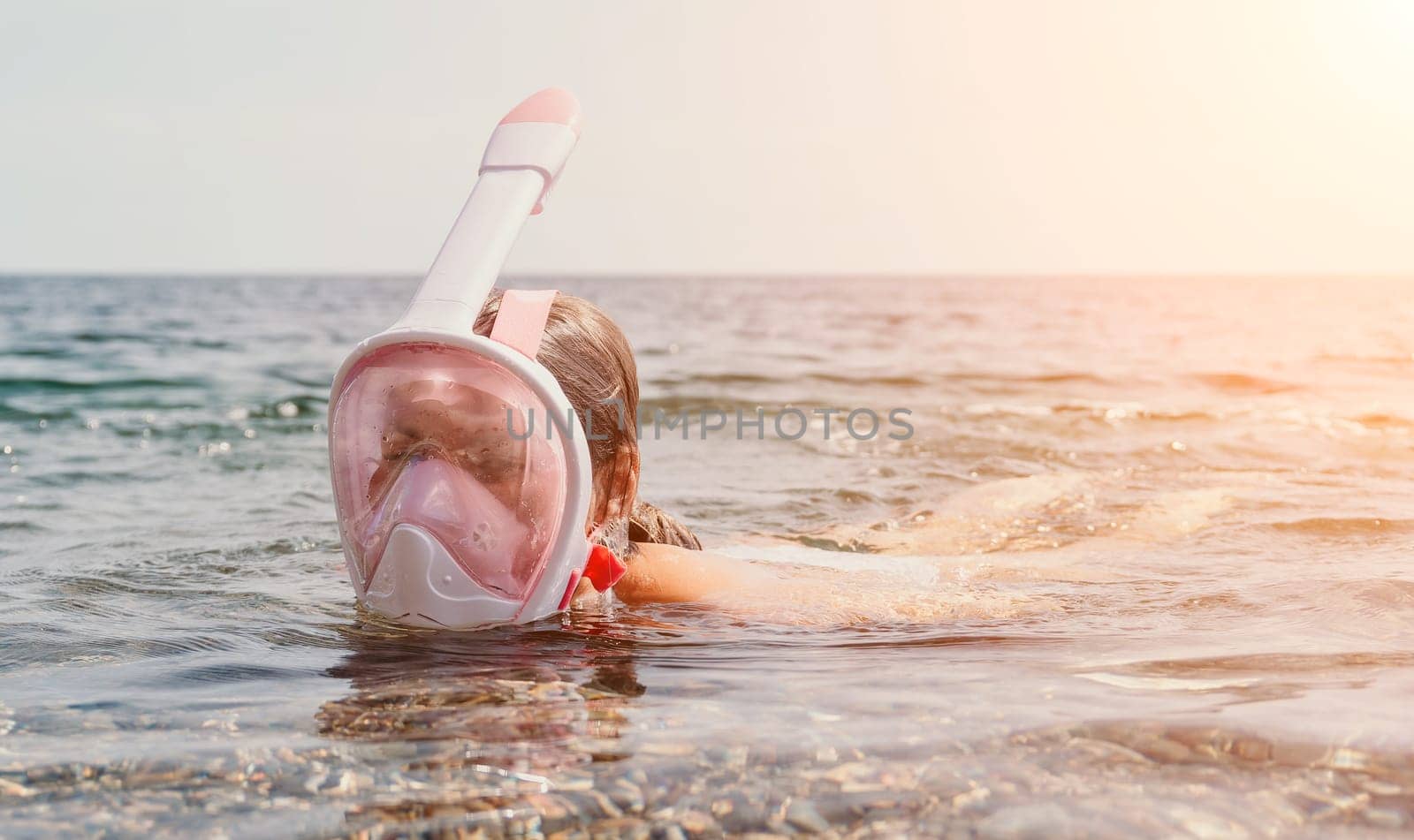 Young happy woman in white bikini and wearing pink mask gets ready for sea snorkeling. Positive smiling woman relaxing and enjoying water activities with family summer travel holidays vacation on sea. by panophotograph