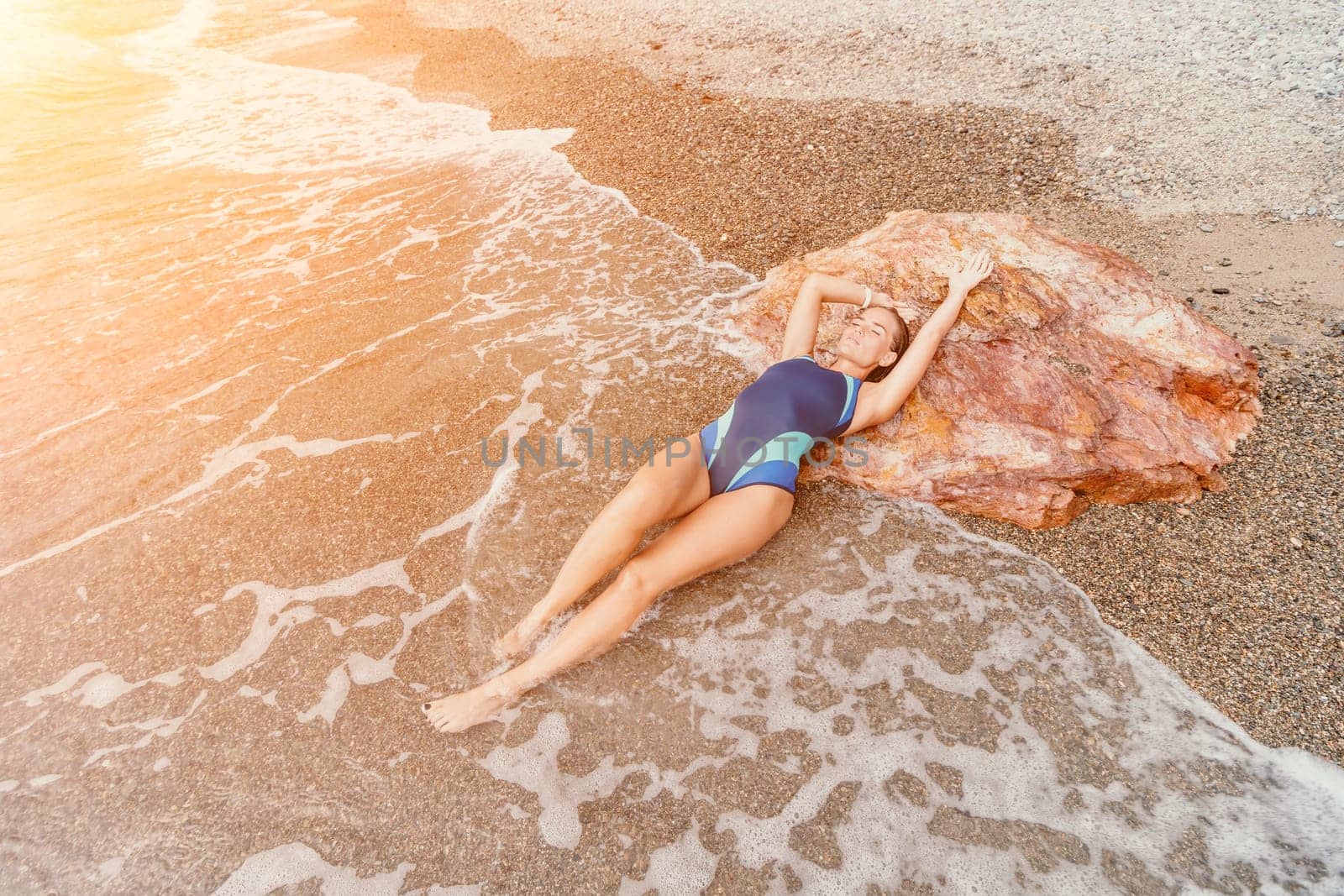 Woman travel sea. Young Happy woman in a long red dress posing on a beach near the sea on background of volcanic rocks, like in Iceland, sharing travel adventure journey