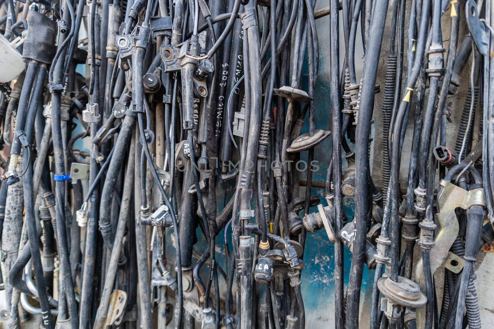 used car tubes and electrical wires hanging on the wall at junkyard market by z1b