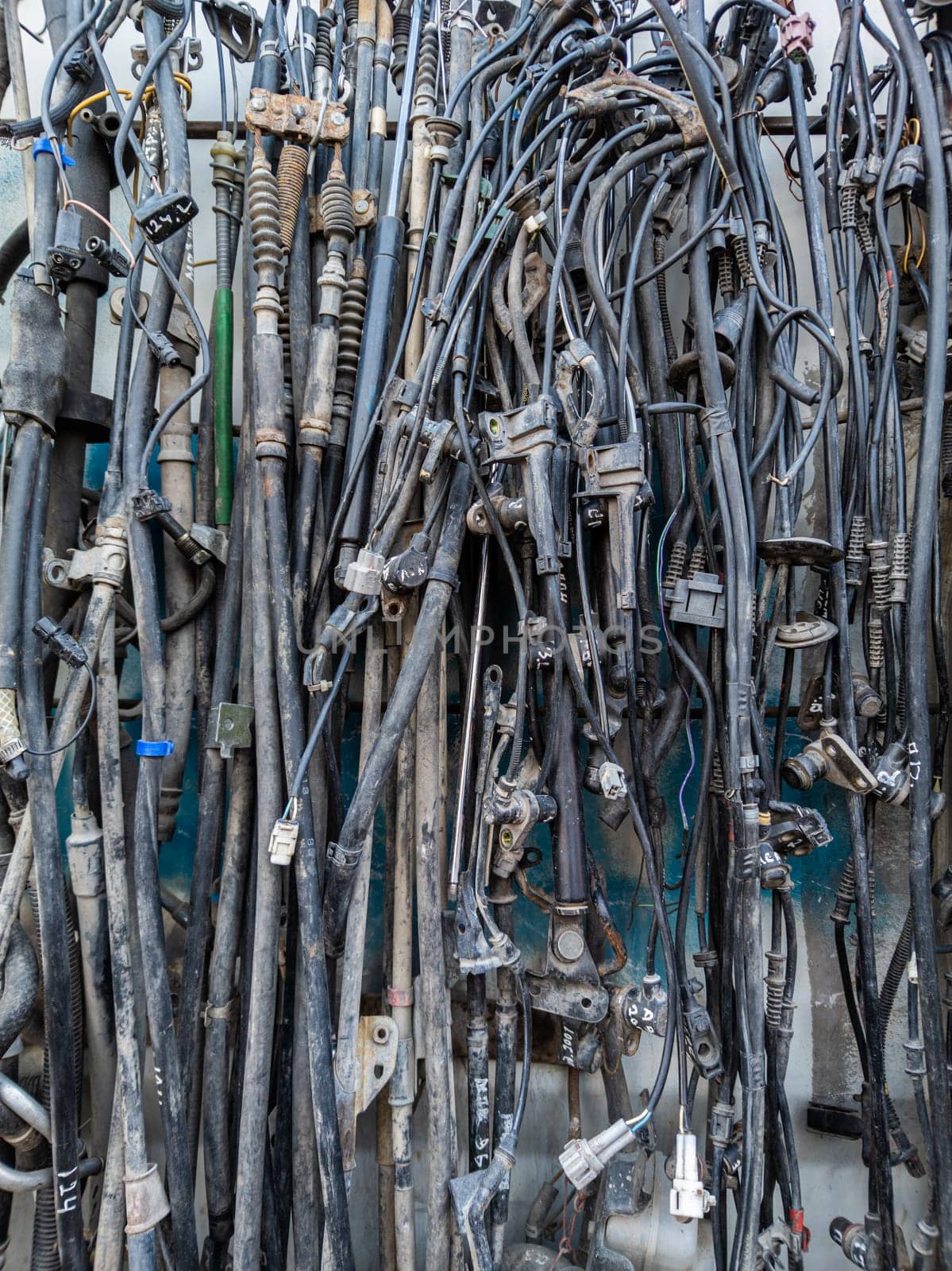 used car tubes and electrical wires hanging on the wall at junkyard market by z1b