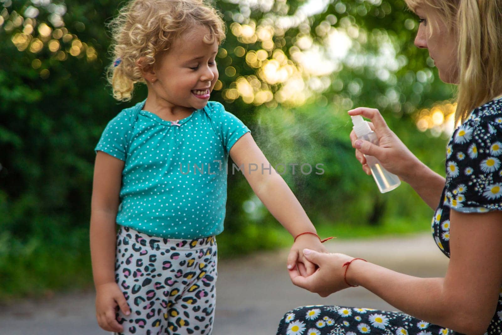 Mom sprays her child with mosquito repellent. Selective focus. by yanadjana