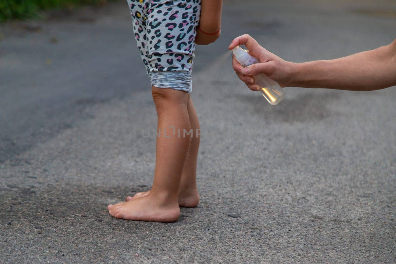Mom sprays her child with mosquito repellent. Selective focus. Nature.