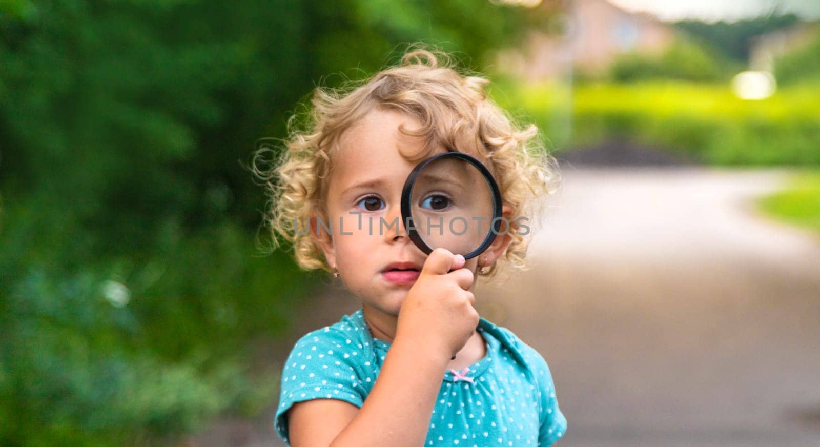 A child looks through a magnifying glass in nature. Selective focus. Kid.