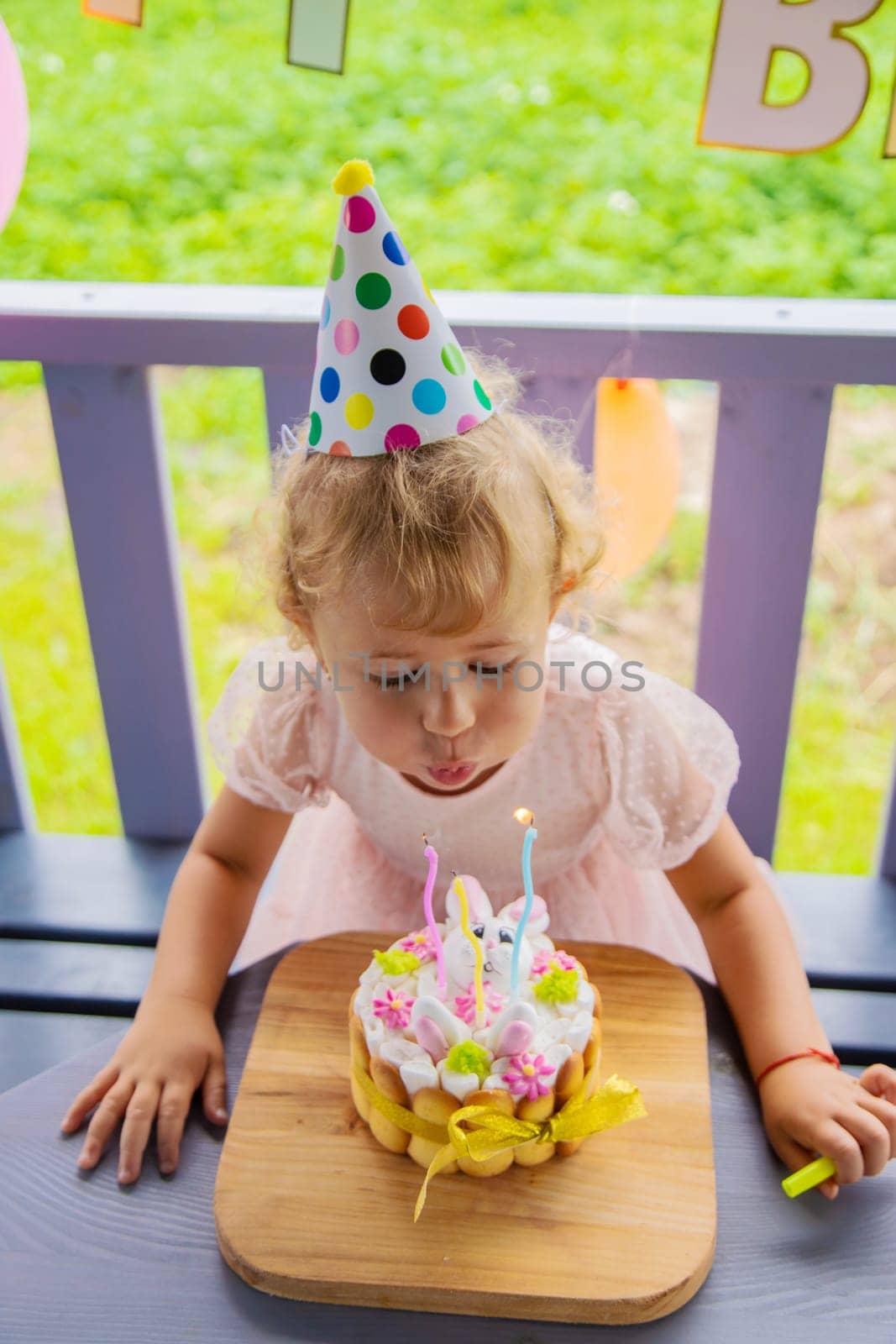 A three year old child blows candles on a cake. Selective focus. Kid.