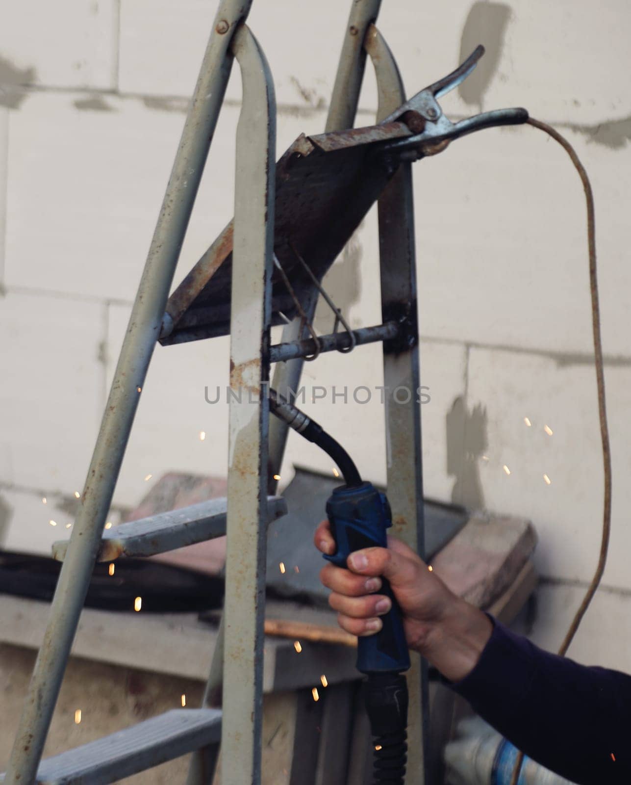 A master welds metal. Selective focus. Hand.