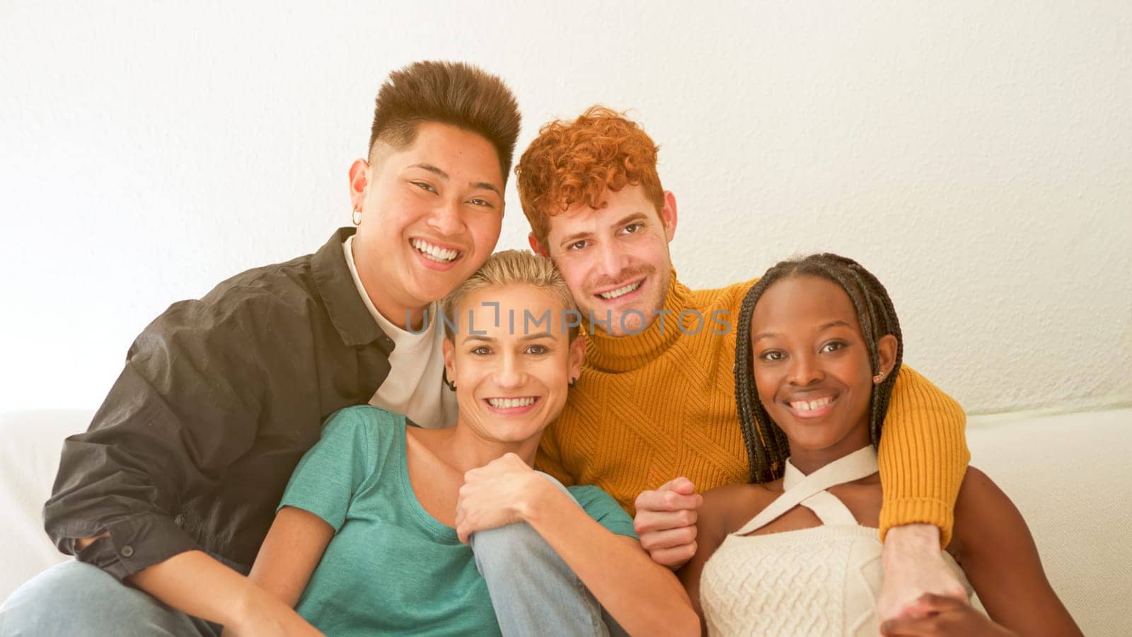 Multiethnic friends looking at camera laughing sitting on the sofa