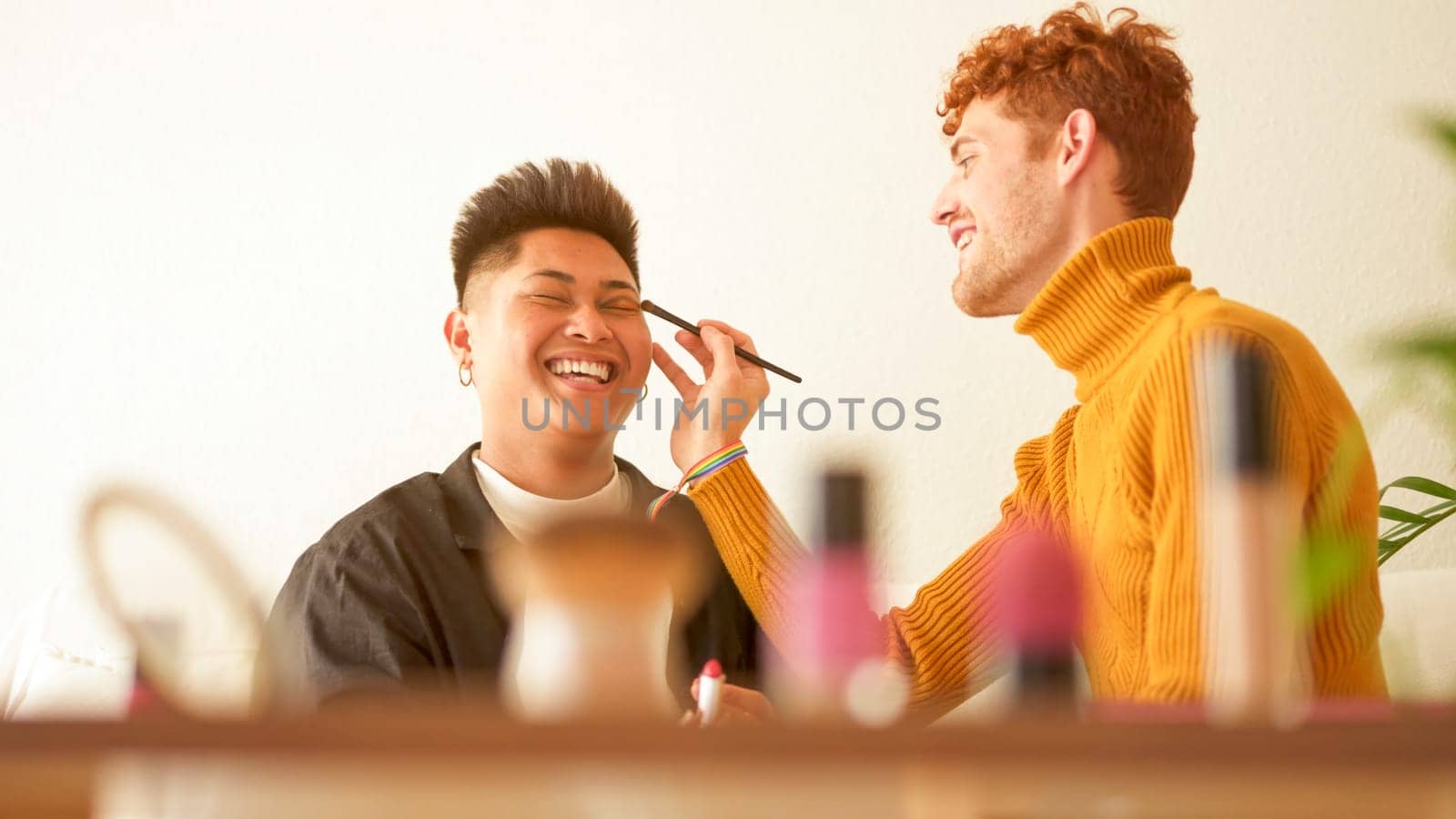 Some cosmetic on a shelf while gay couple applying make up