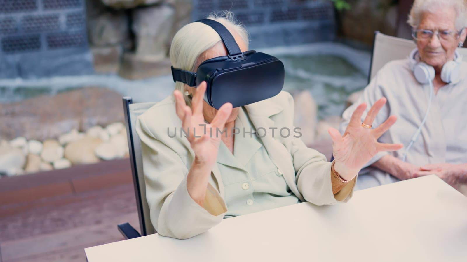 Picture of a senior woman gesturing while using virtual reality goggle in geriatric