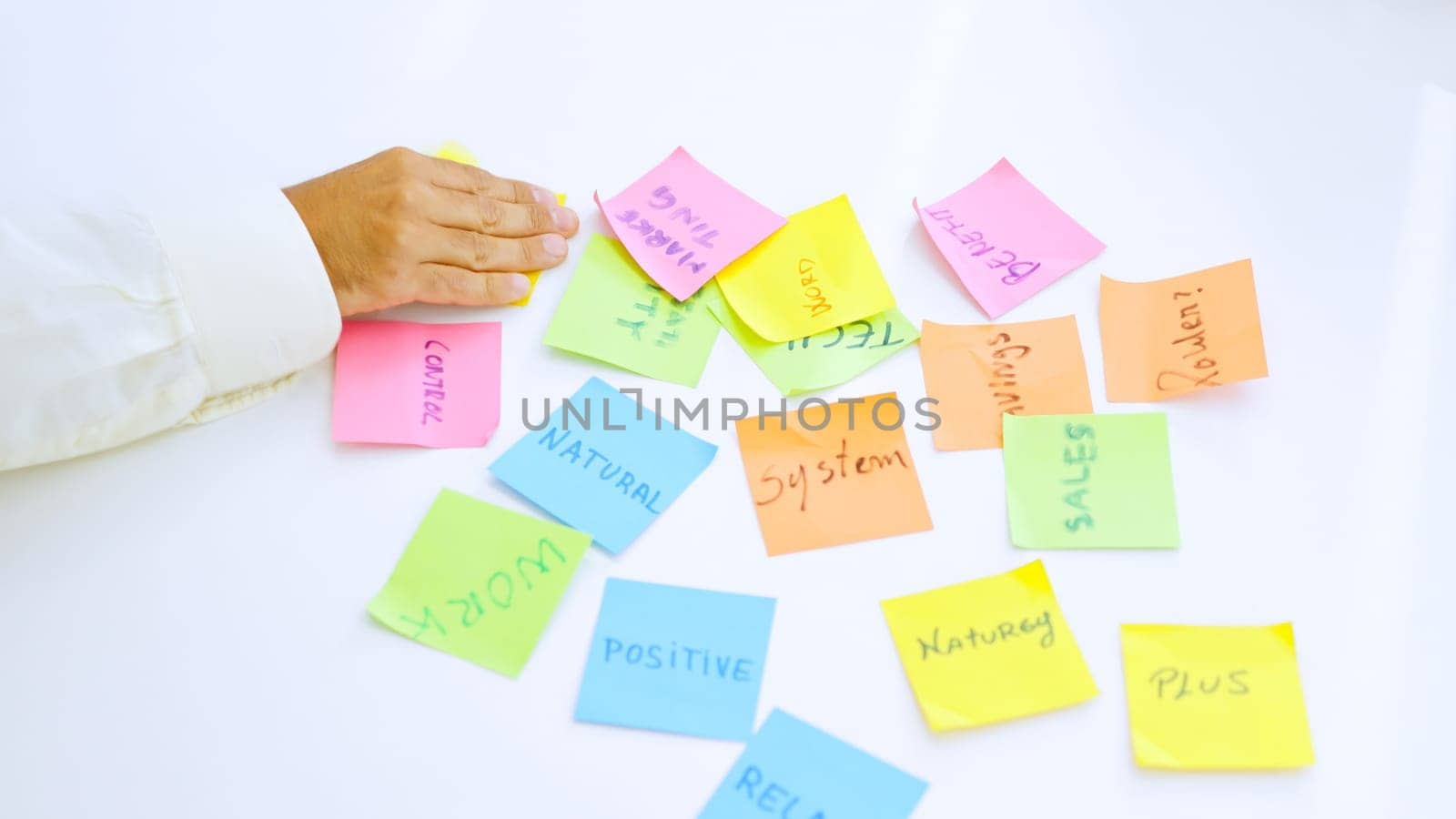 close-up picture of people using adhesive notes to write ideas on a table