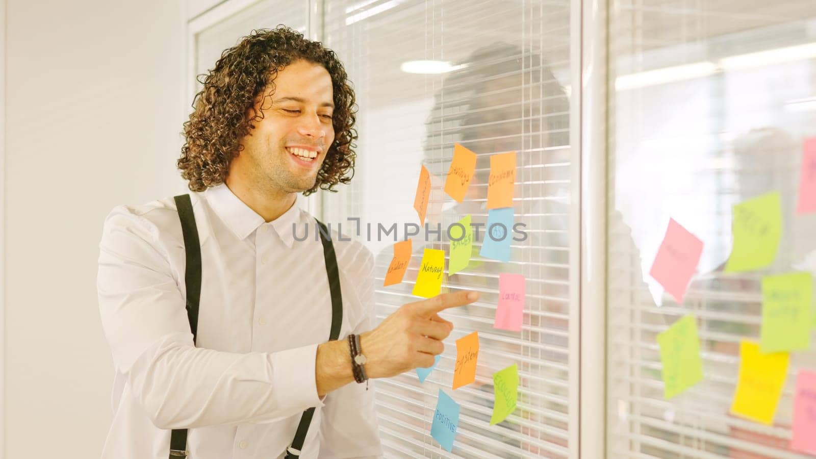 Man pointing a post-it presenting ideas in a meeting by ivanmoreno