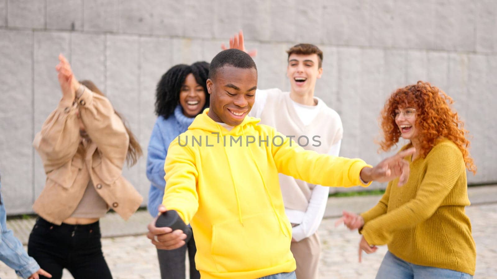 A young group of multi-ethnic happy friends dancing excited in the city