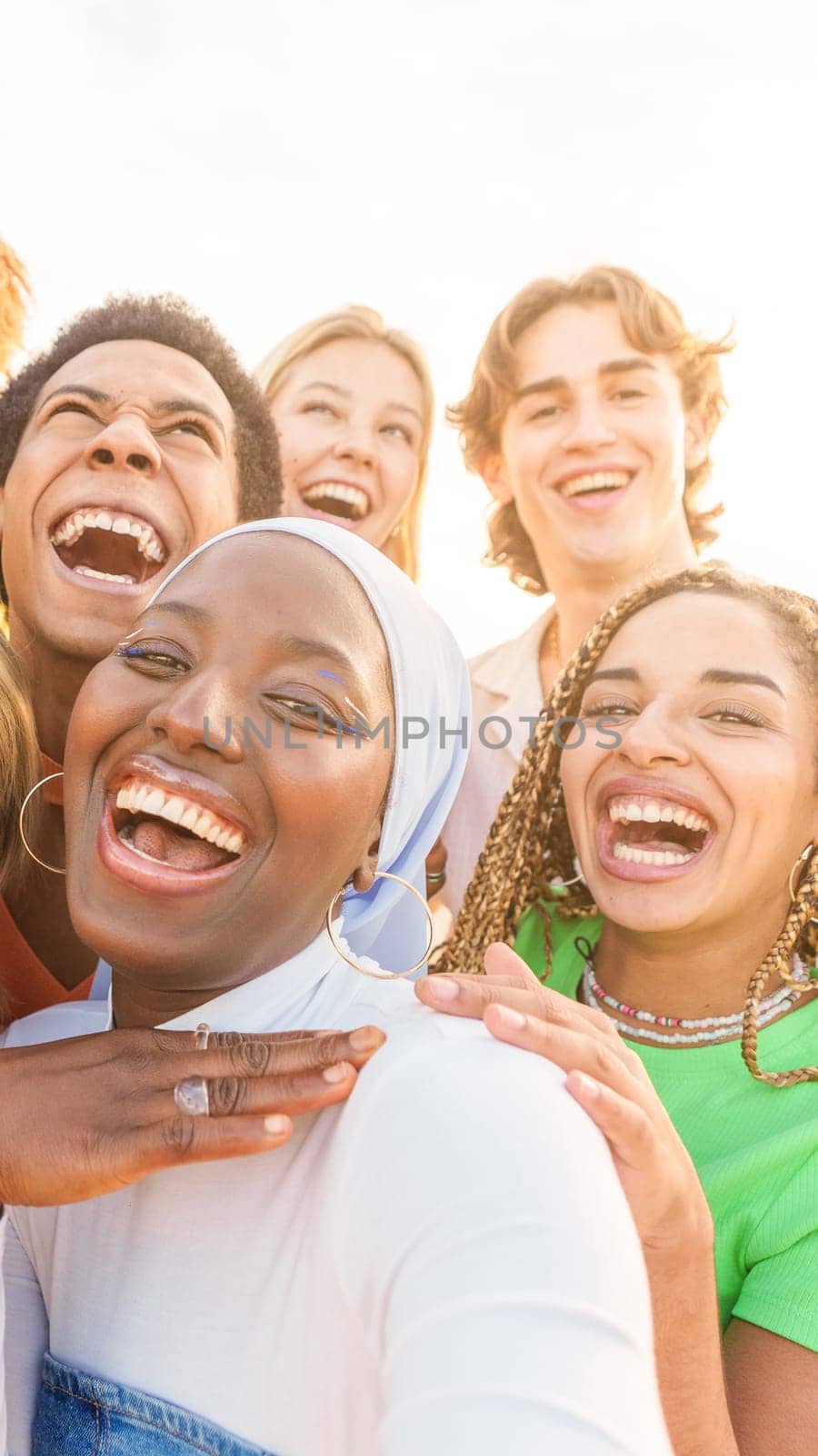 Group of smiling crazy multi-ethnic people taking selfies during sunset