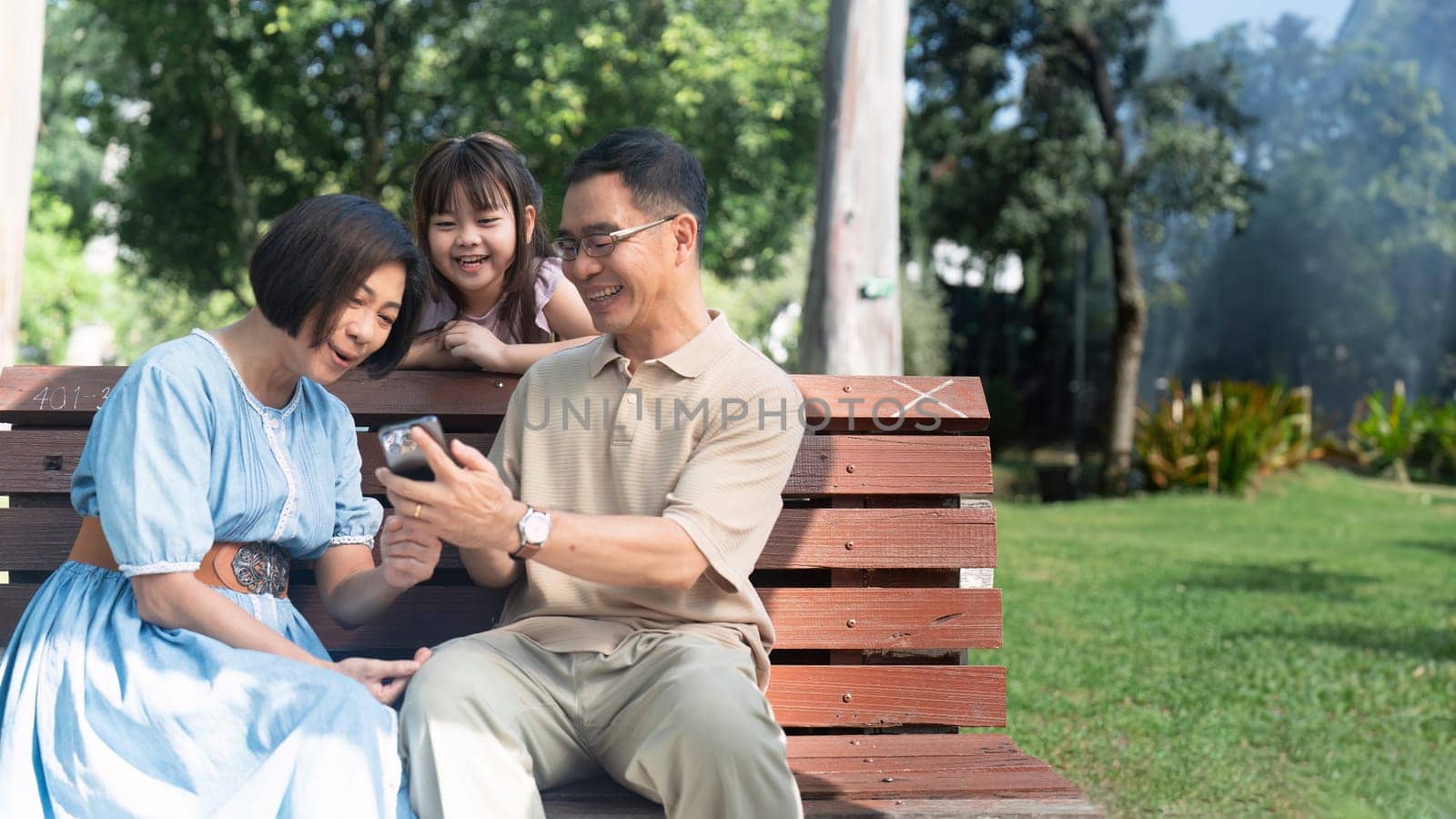 family picnic with child and grandparent and using mobile, outdoor wellness lifestyle by itchaznong