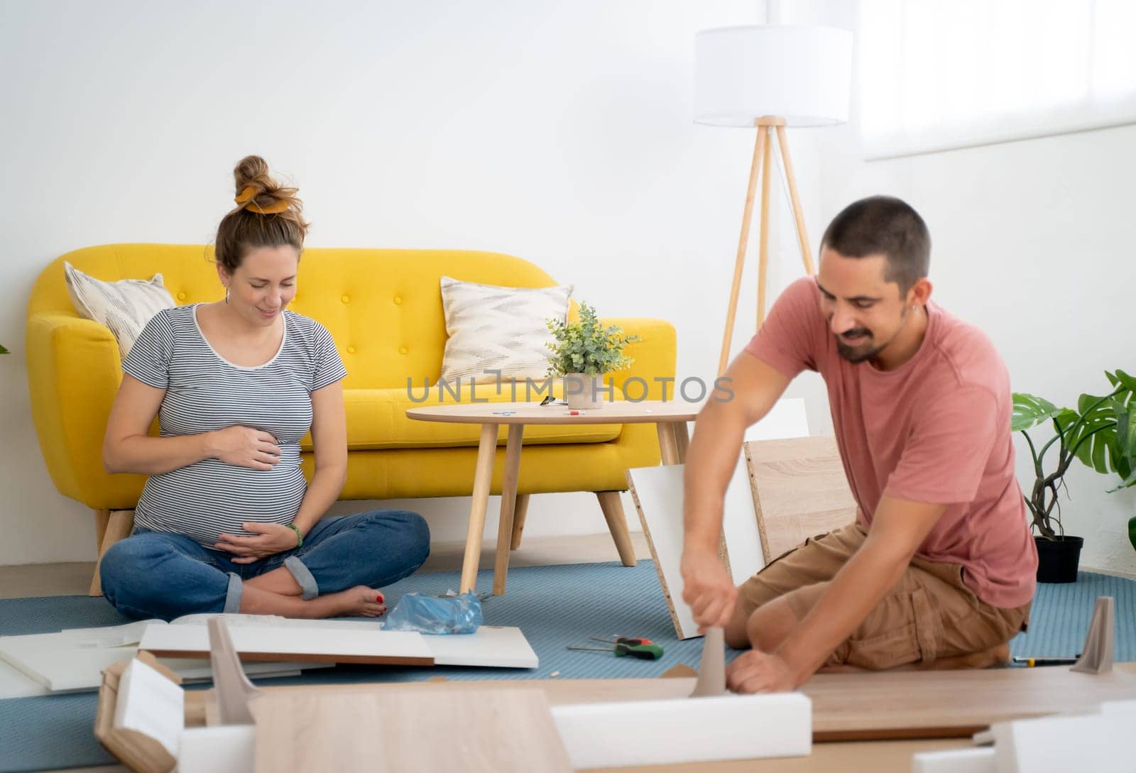 Pregnant couple assembling furniture arranging the house waiting for the arrival of a new baby. High quality photo