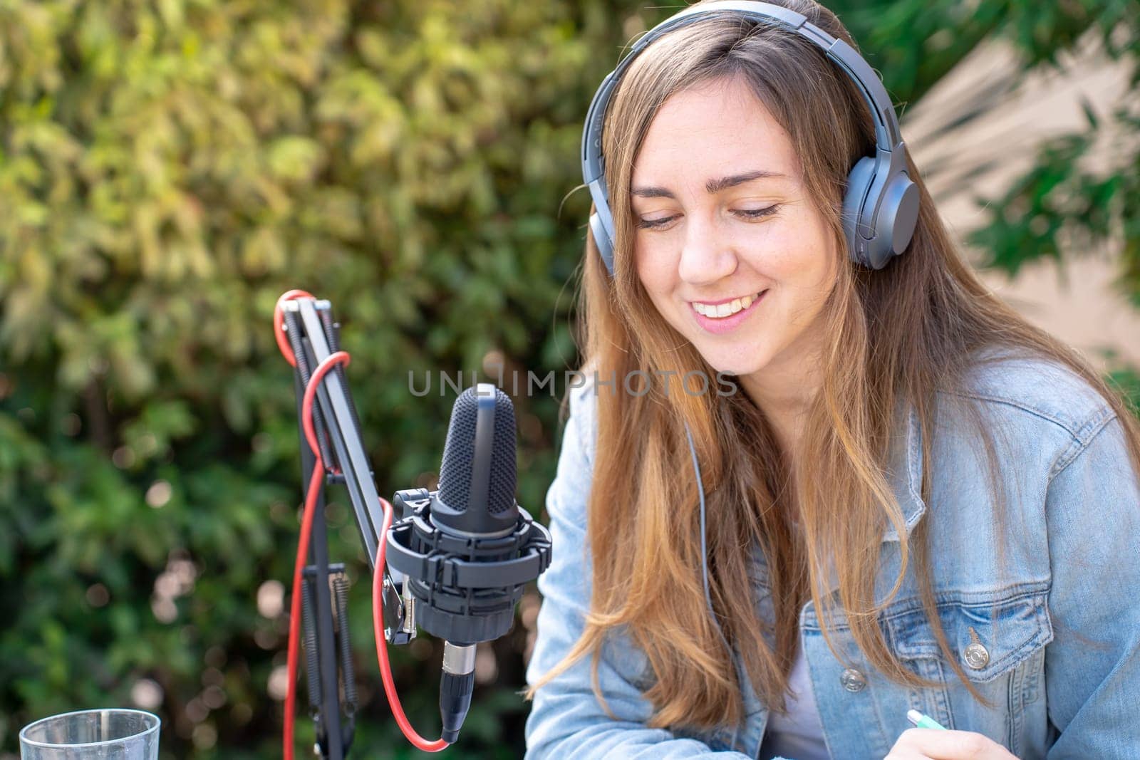 Attractive woman recording radio podcast - Young girl talking during live stream session outdoor. High quality photo
