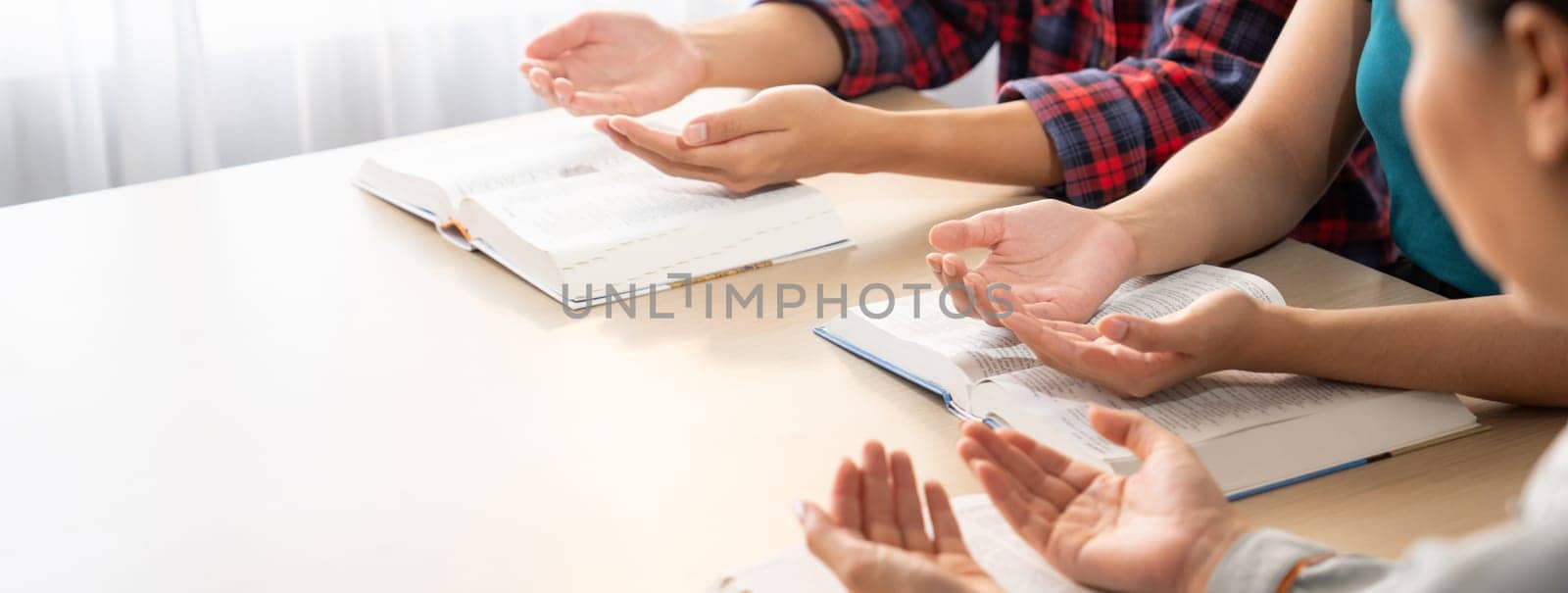 Cropped image of diversity people hand praying together at wooden church on bible book. Group of believer hold hand together faithfully. Concept of hope, religion, faith, god blessing. Burgeoning.