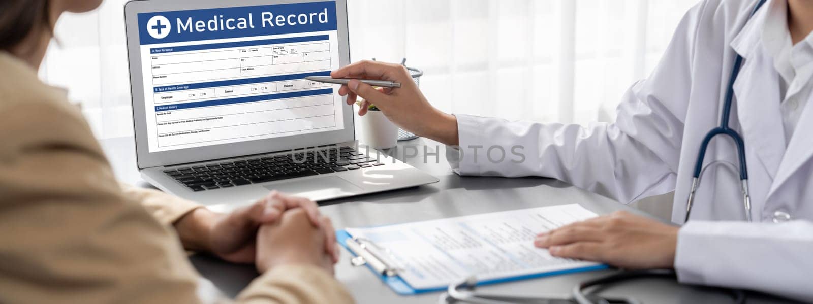 Doctor show medical diagnosis report on laptop and providing compassionate healthcare consultation while being supportive and holding young patient hand in doctor clinic office. Neoteric