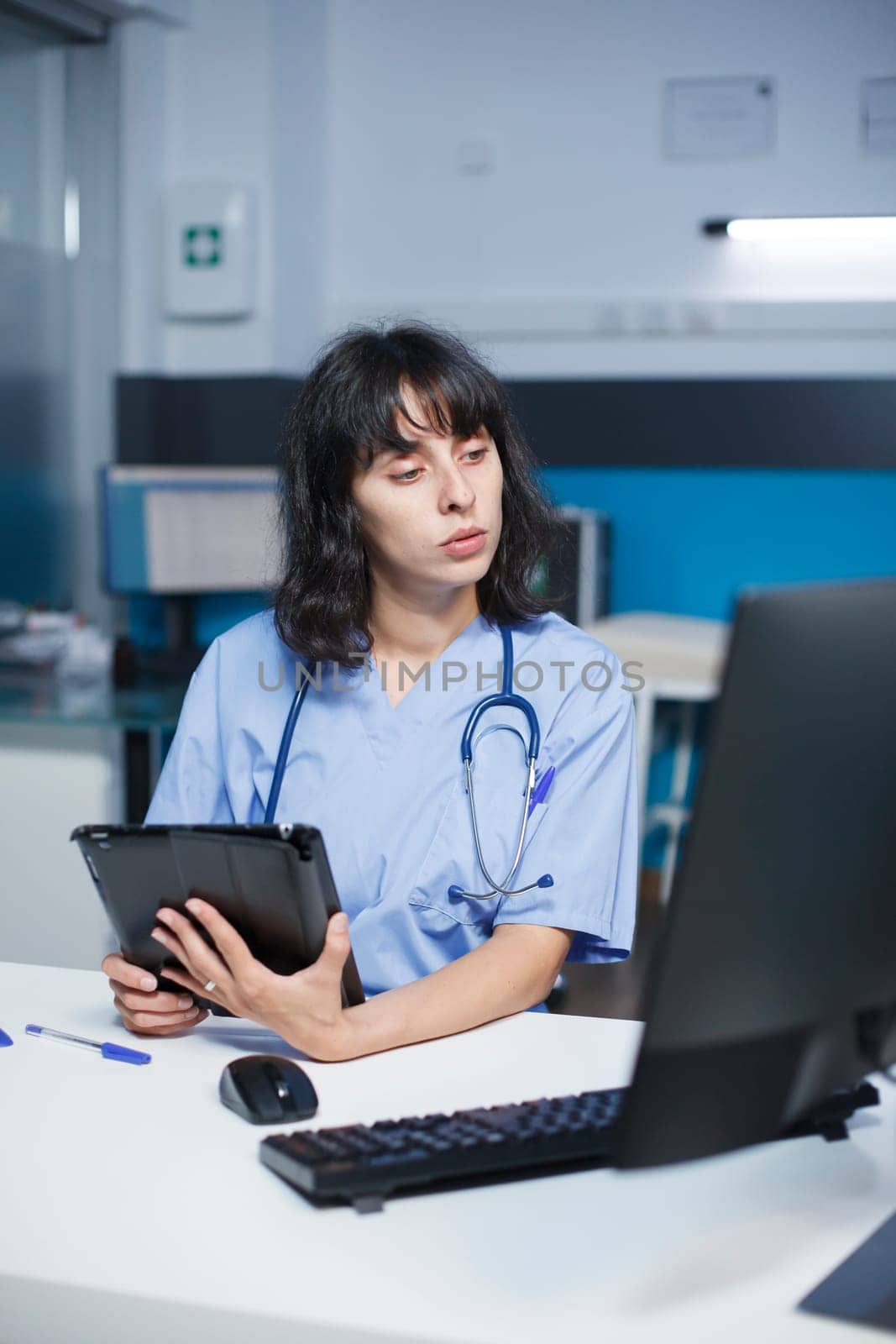 Nurse reviewing files with technology by DCStudio