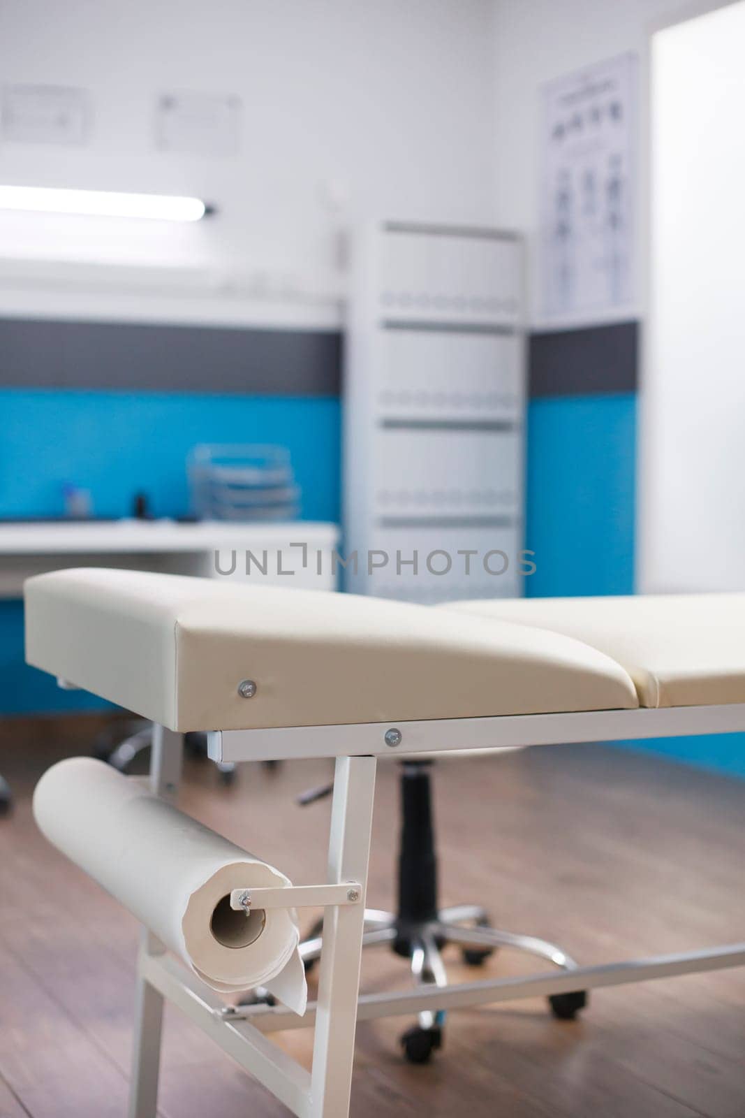 Close-up shot of an empty examination bed in a hospital room. The detailed image showcases a clinic office where patients may make appointments and get consultations.