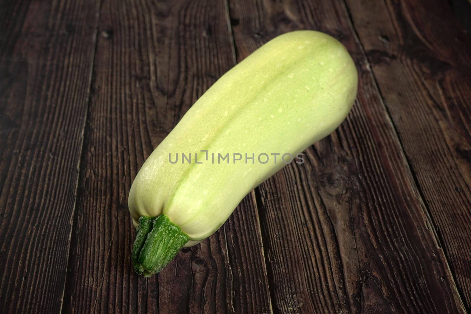 Light green zucchini courgette on old dark wooden desk