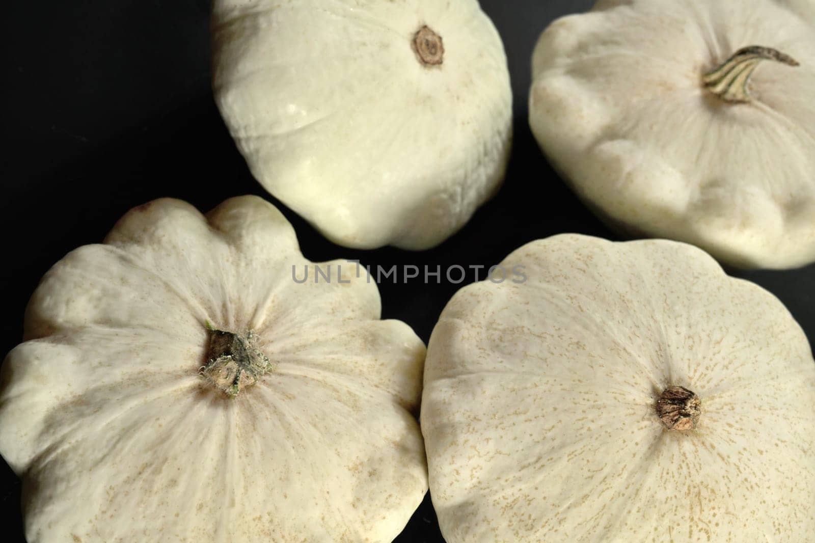 Group of pattypan squashes on dark wood board, closeup detail by Ivanko