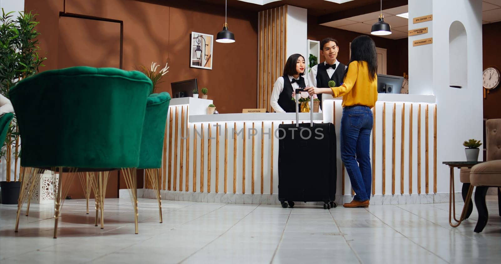 Asian woman approaching front desk in hotel lobby by DCStudio