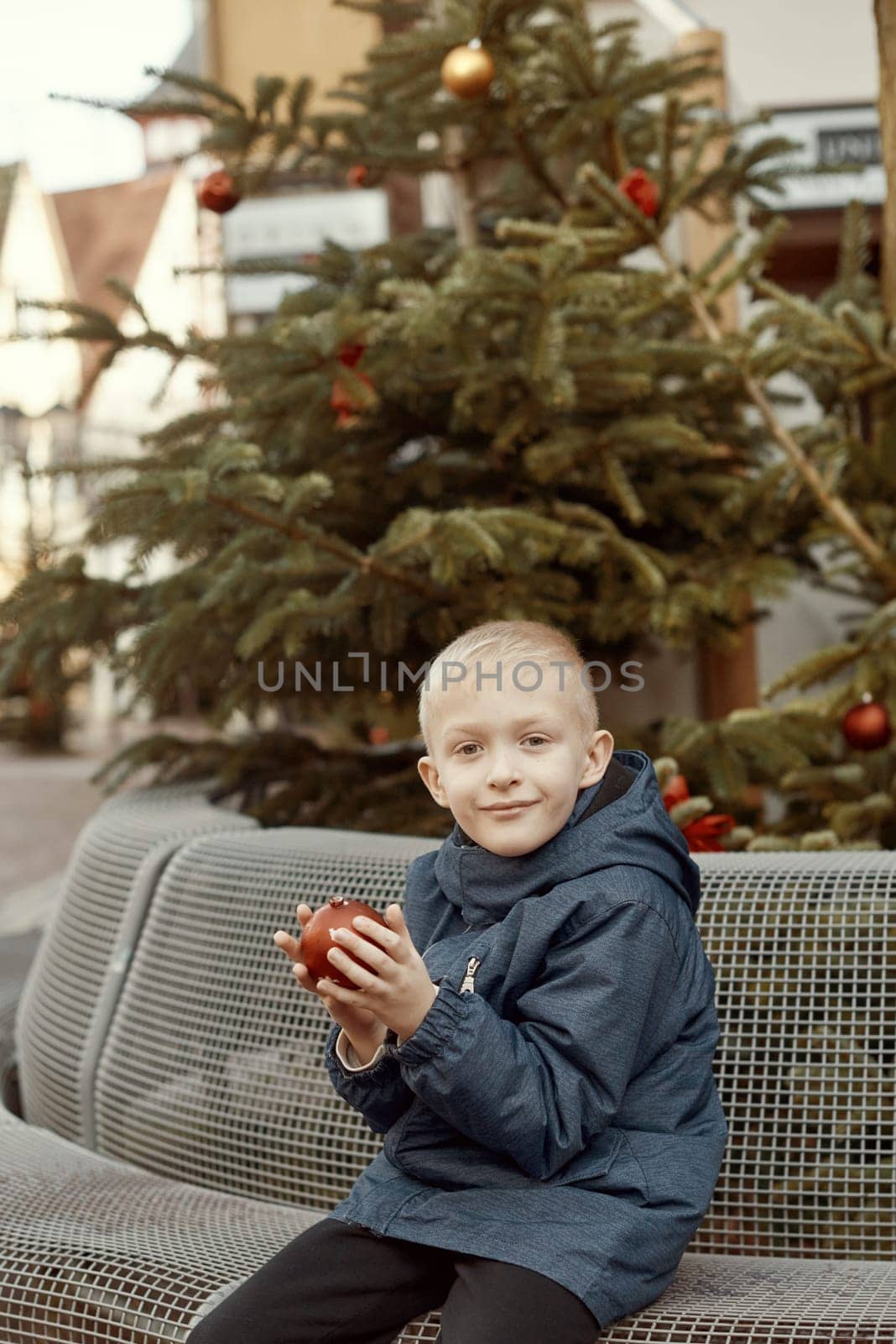 Winter Wonderland Delight: 8-Year-Old Boy with Christmas Decor by Vintage Fountain. by Andrii_Ko
