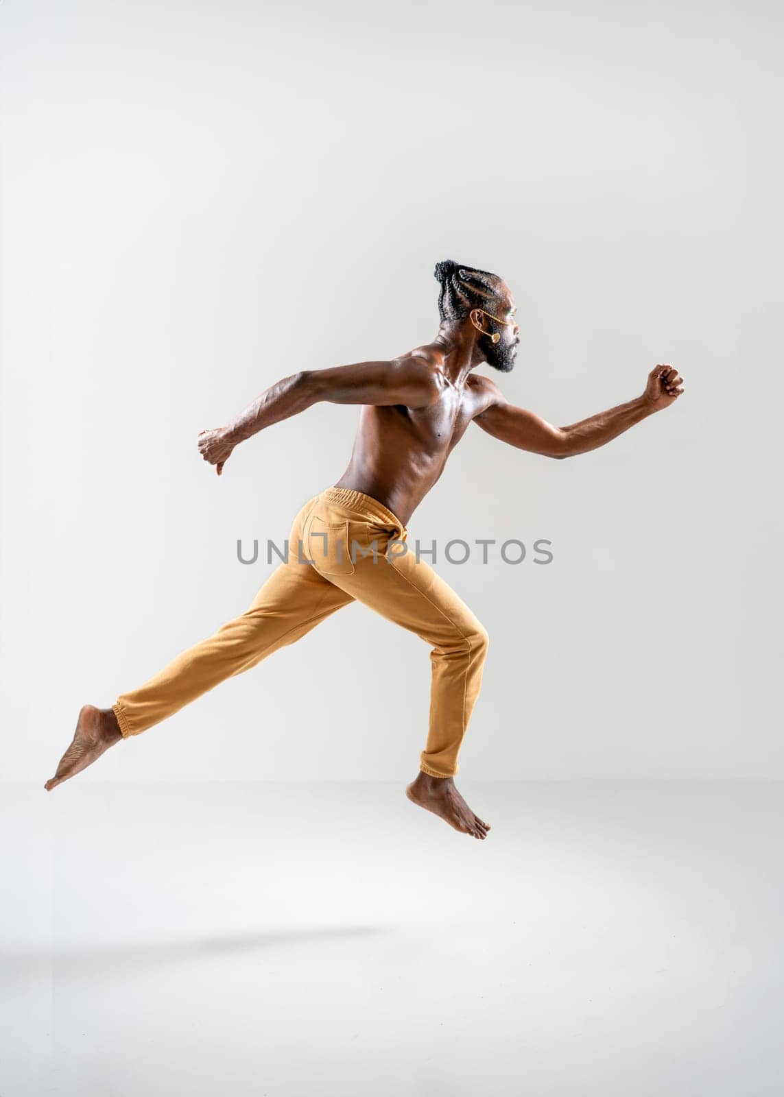 Full length of shirtless African American gay man running isolated on white background. Side view of athletic man jogging in white studio. Equality concept.