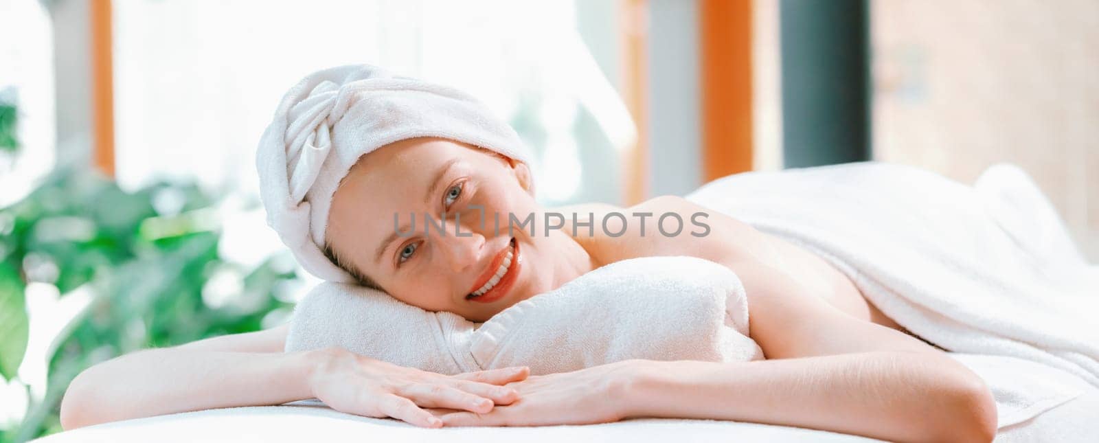 Beautiful young woman relaxes on a spa bed surrounded by nature. ready for a body massage. Attractive female in white towel lying peacefully during waiting for body massage. Close up. Tranquility