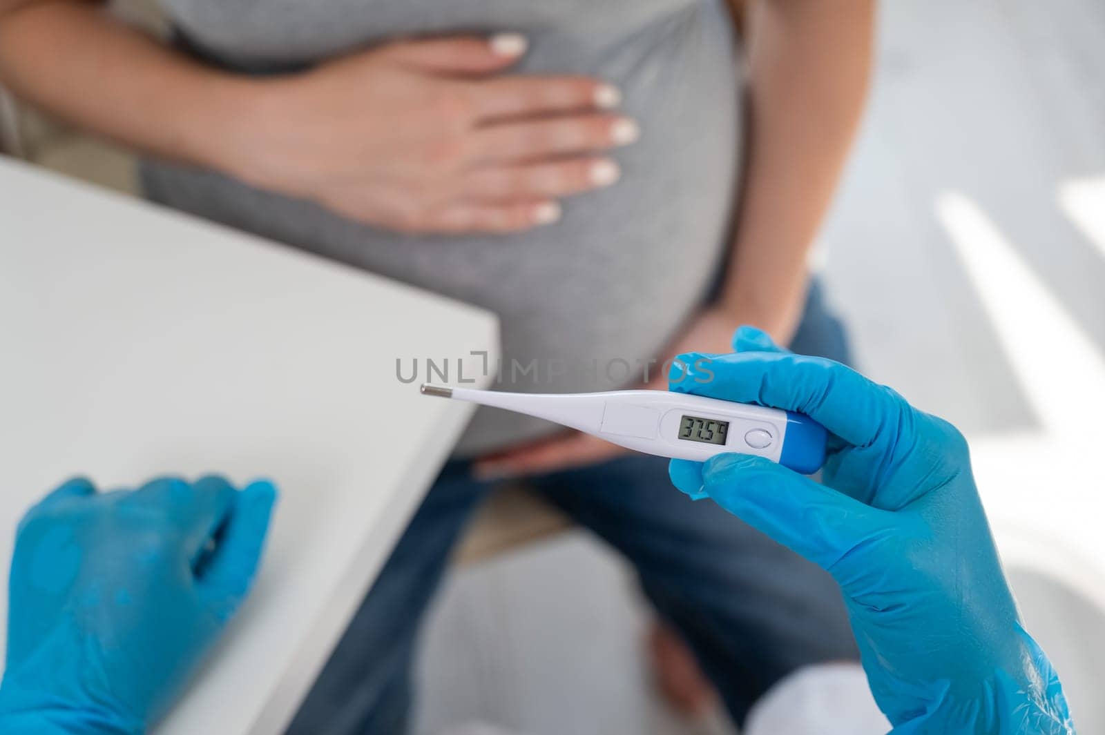 Pregnant woman with fever at doctor's appointment. Therapist holds an electronic thermometer with a temperature of 37.5. by mrwed54