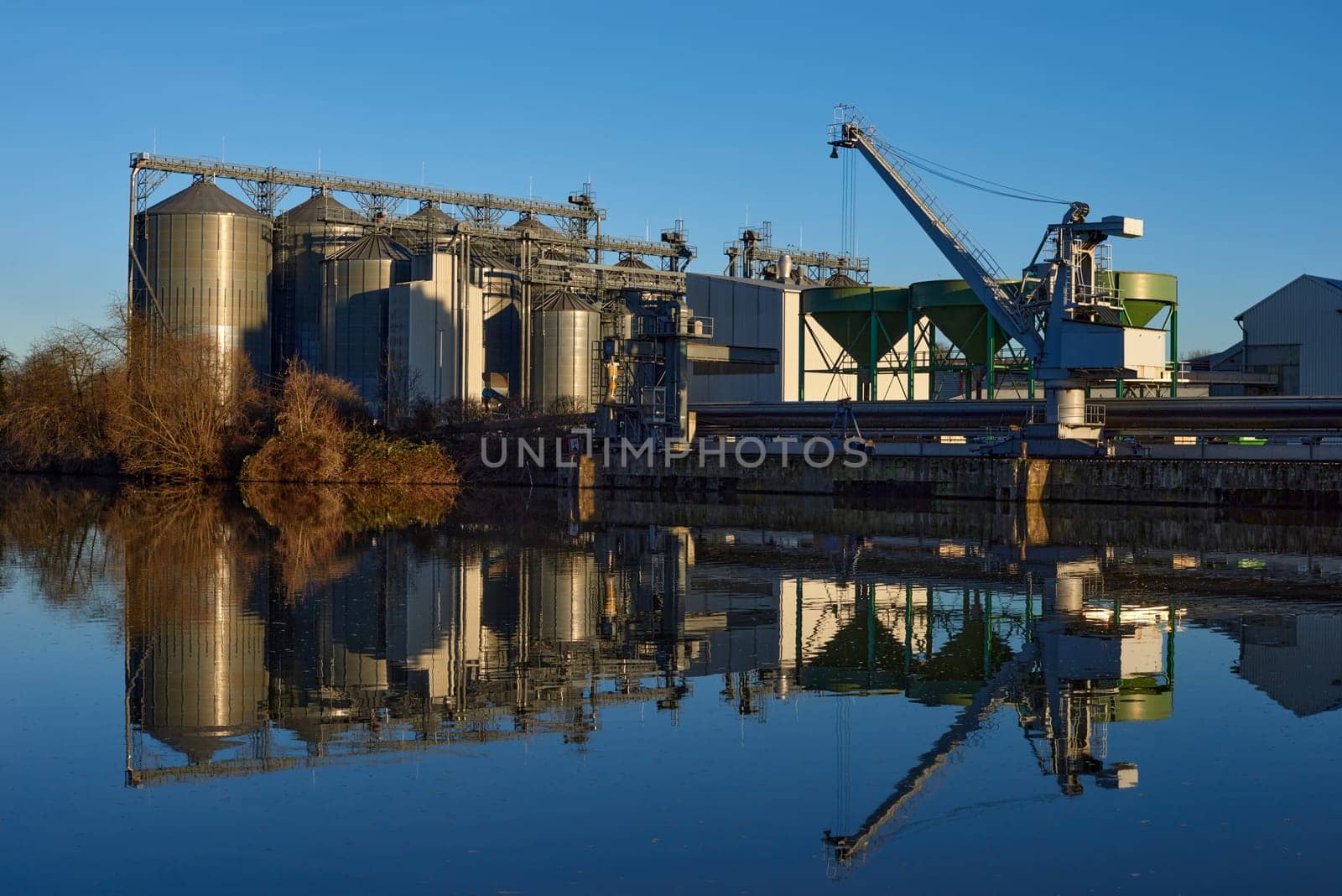 Riverside Manufacturing at Dusk. Environmental Technology and Production. Riverside Manufacturing Hub. Eco-Friendly Technology and Production. industry and the environment, showcasing the integration of sustainable practices. by Andrii_Ko