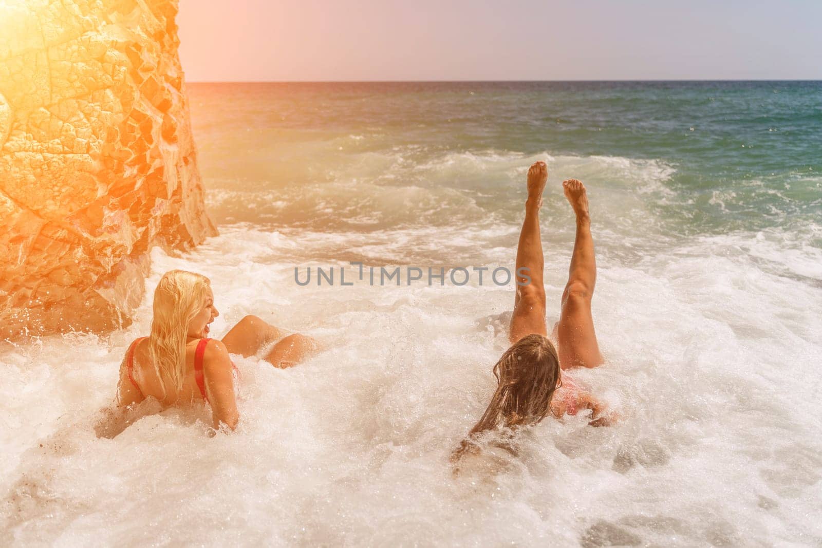 Women ocean play. Seaside, beach daytime, enjoying beach fun. Two women in red swimsuits enjoying themselves in the ocean waves. by Matiunina