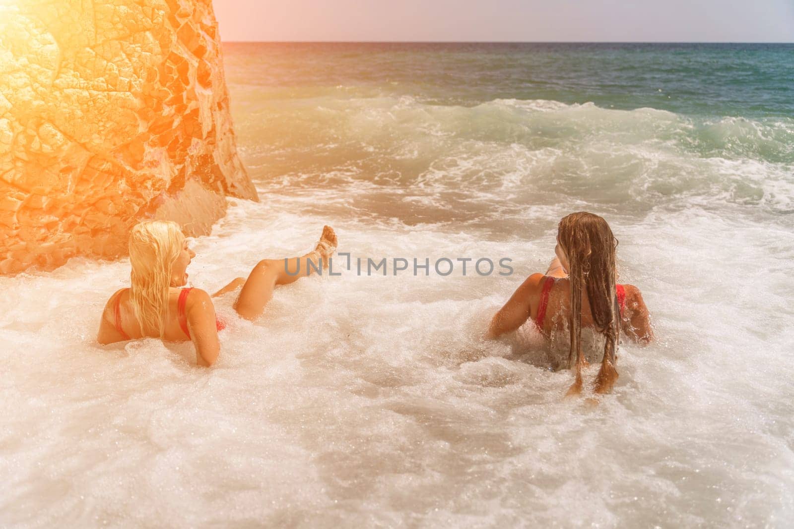 Women ocean play. Seaside, beach daytime, enjoying beach fun. Two women in red swimsuits enjoying themselves in the ocean waves. by Matiunina