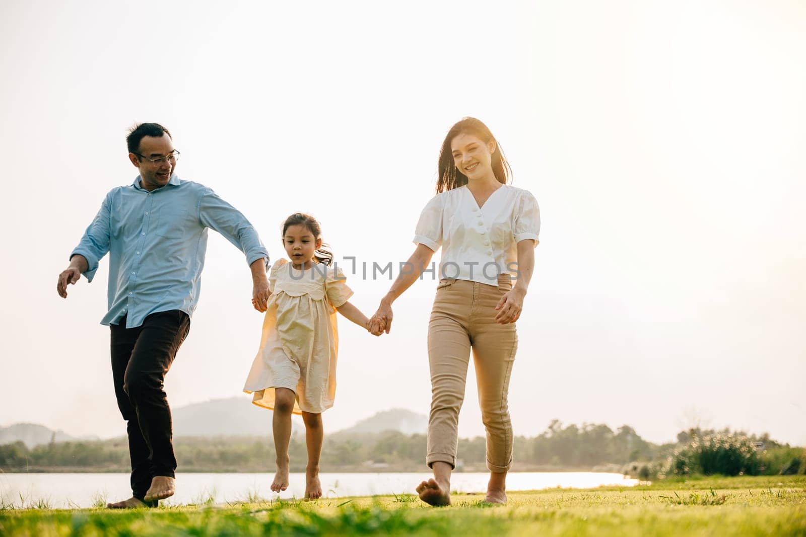 Asian family walking and holding hands in a beautiful springtime park by Sorapop