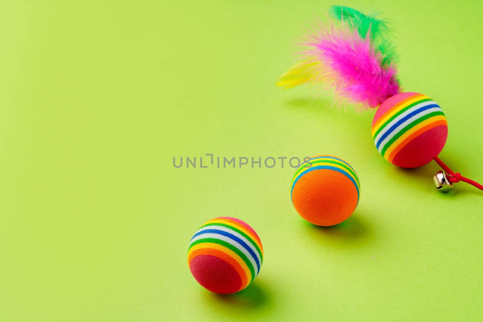 Colorful pet toys balls on green background close up