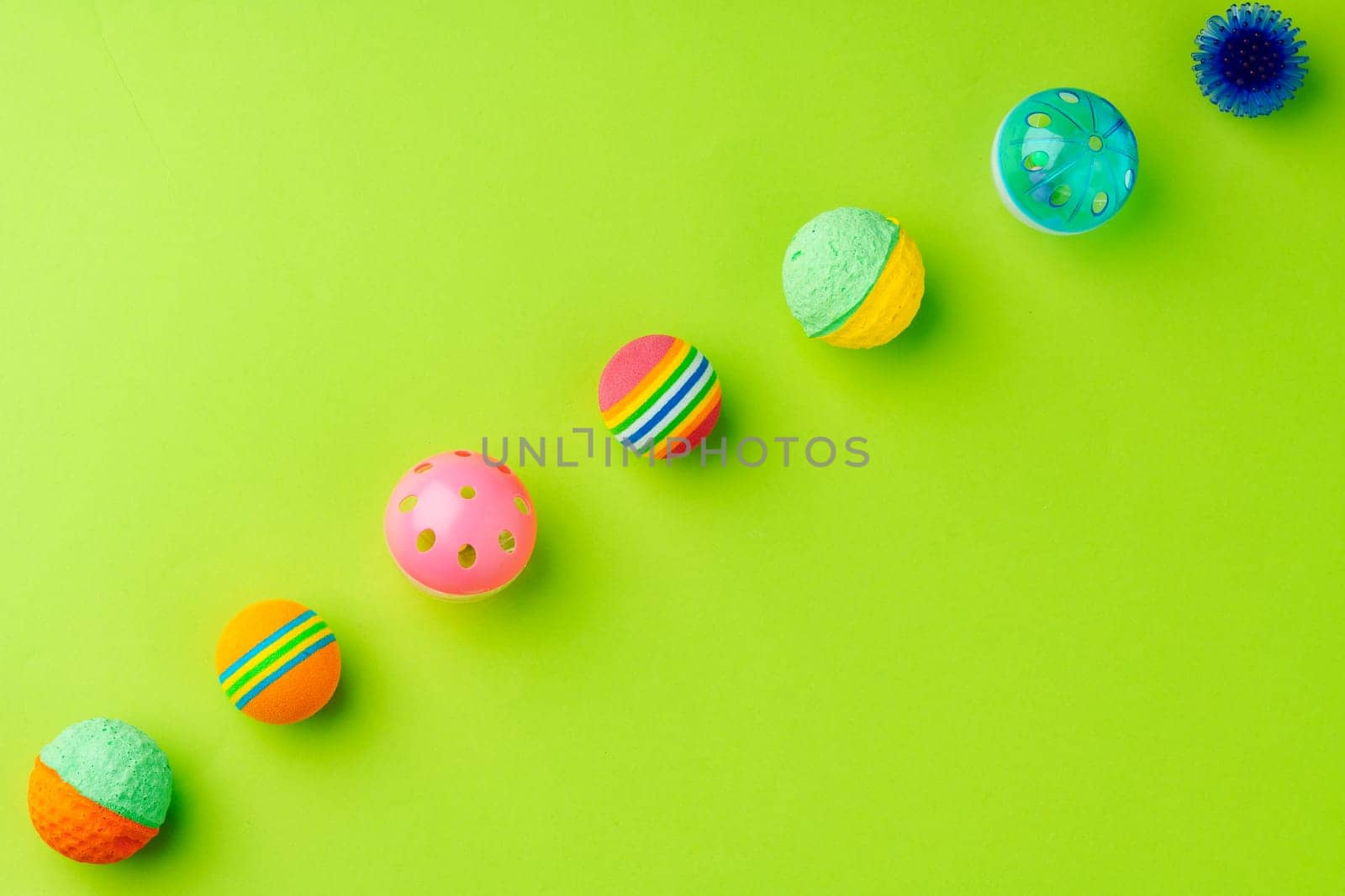 Colorful pet toys balls on green background close up