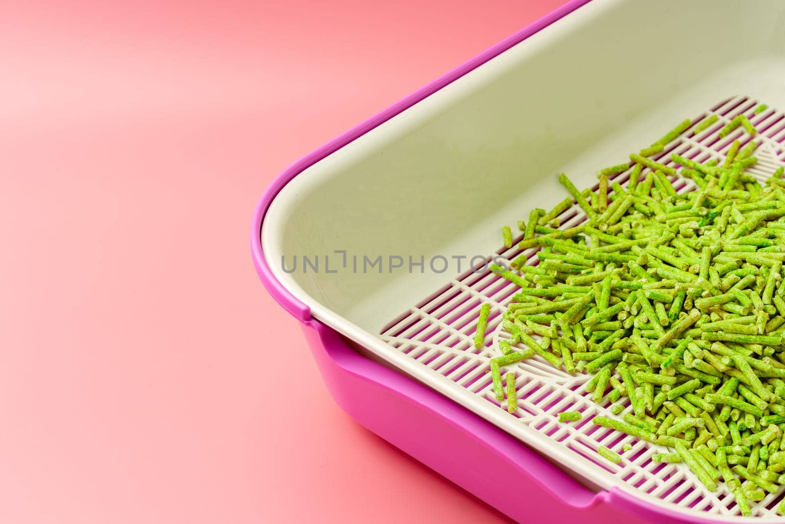 Pet litter box with bio filler on pink background close up