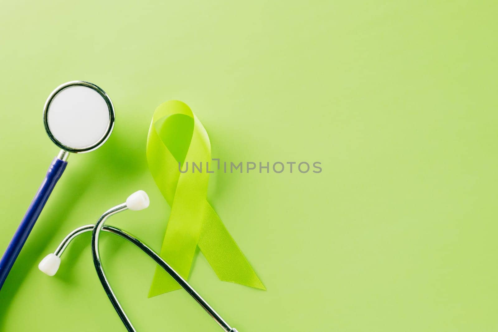 Green awareness ribbon and doctor stethoscope symbol of Gallbladder and Bile Duct Cancer month on green background with copy space, concept of medical and health care support, World bipolar day