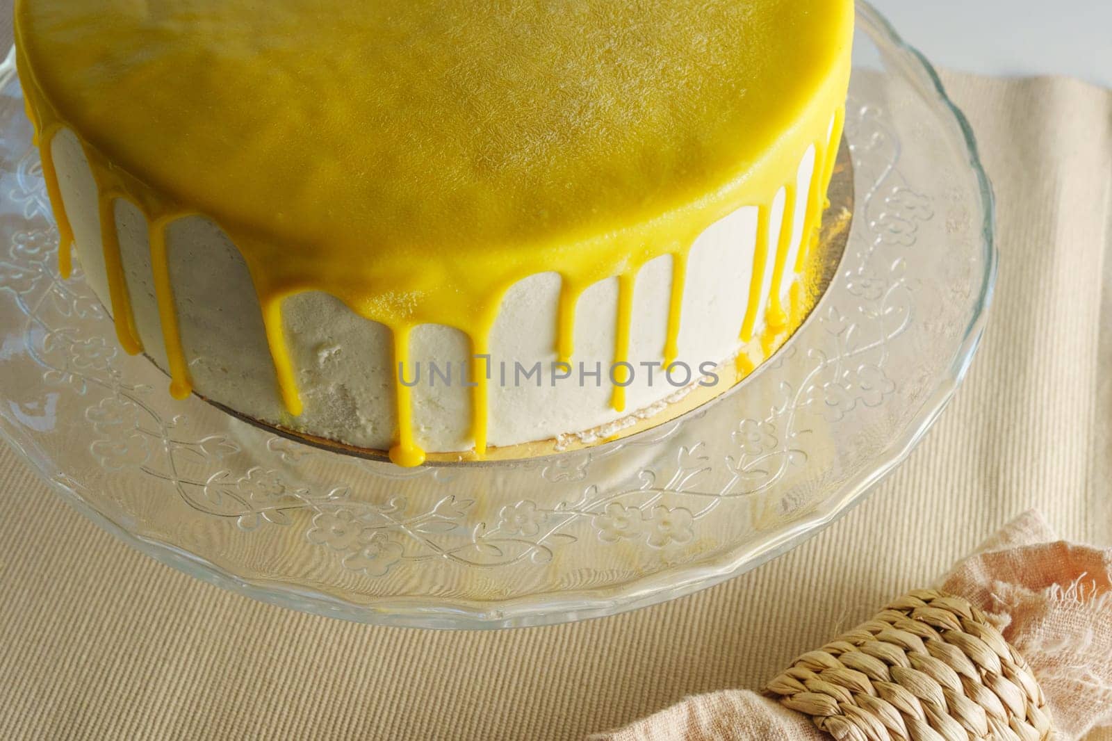 Cake sits elegantly on a glass stand, adorned with a glistening lemon glaze