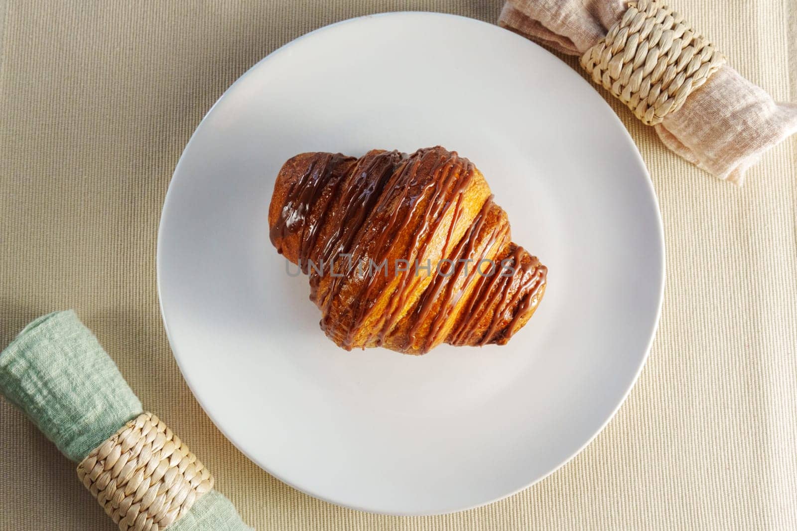 Croissant delicately placed on a pristine white plate, showcasing its buttery layers and inviting aroma. by darksoul72