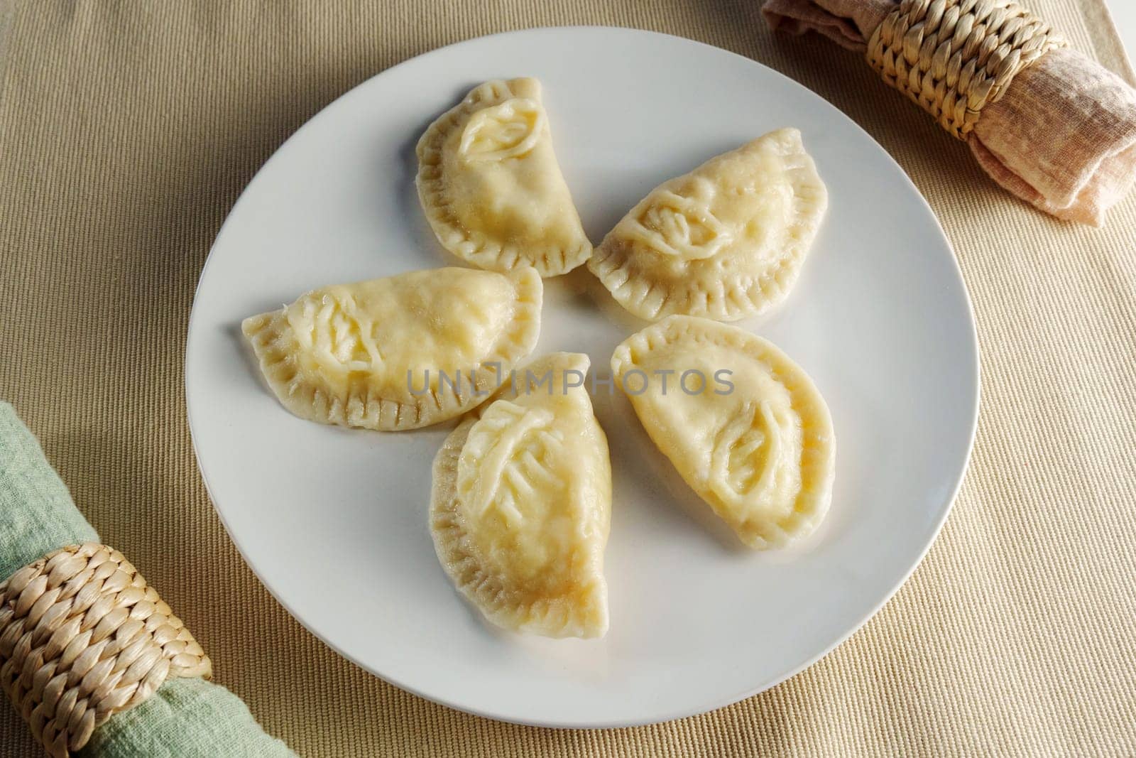 Elegance of perfectly crimped crescent dumplings, or ravioli, presented on a white plate, ready to entice any food connoisseur. by darksoul72