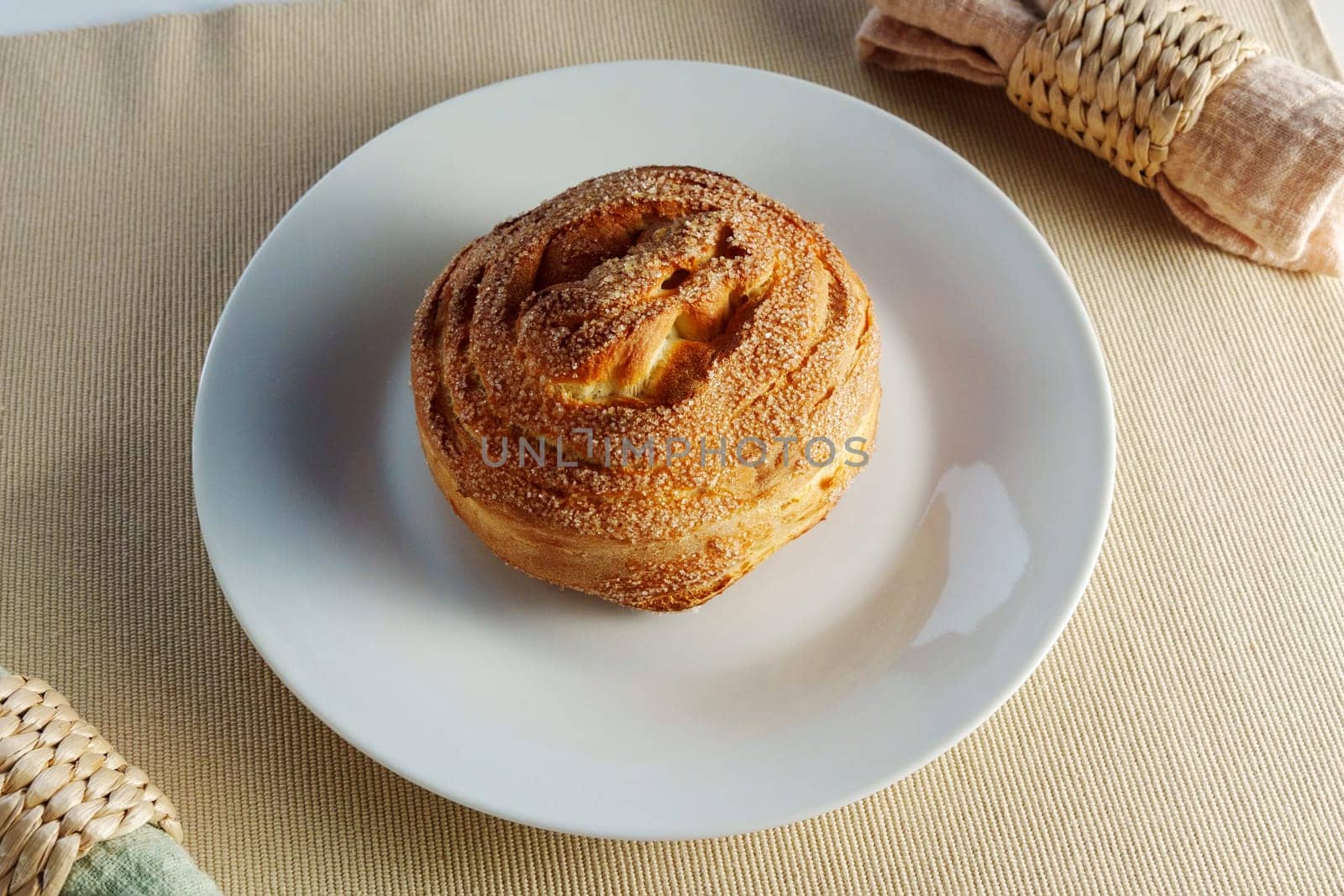 Mouthwatering cinnamon roll takes center stage on a white plate, enticing with its irresistible aroma.