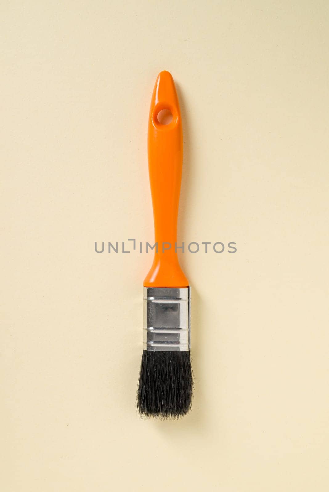 Touch-up paint brush with orange handle on yellow background by Sonat