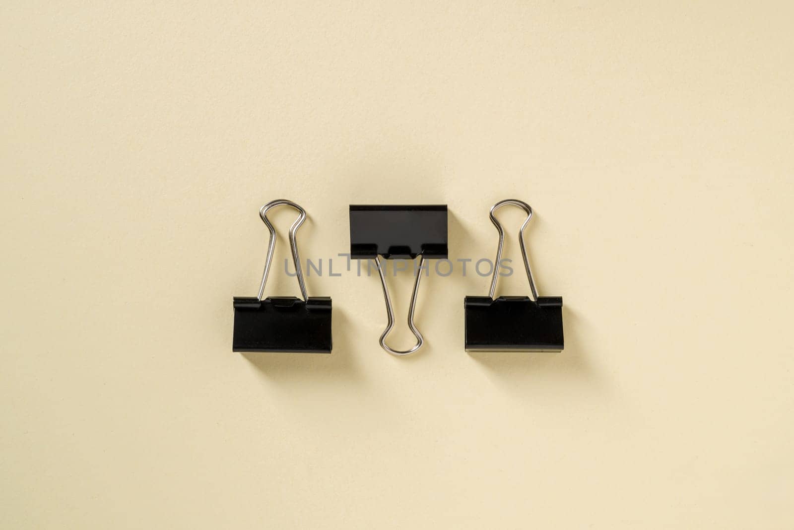 Black binder paper clip on yellow background by Sonat