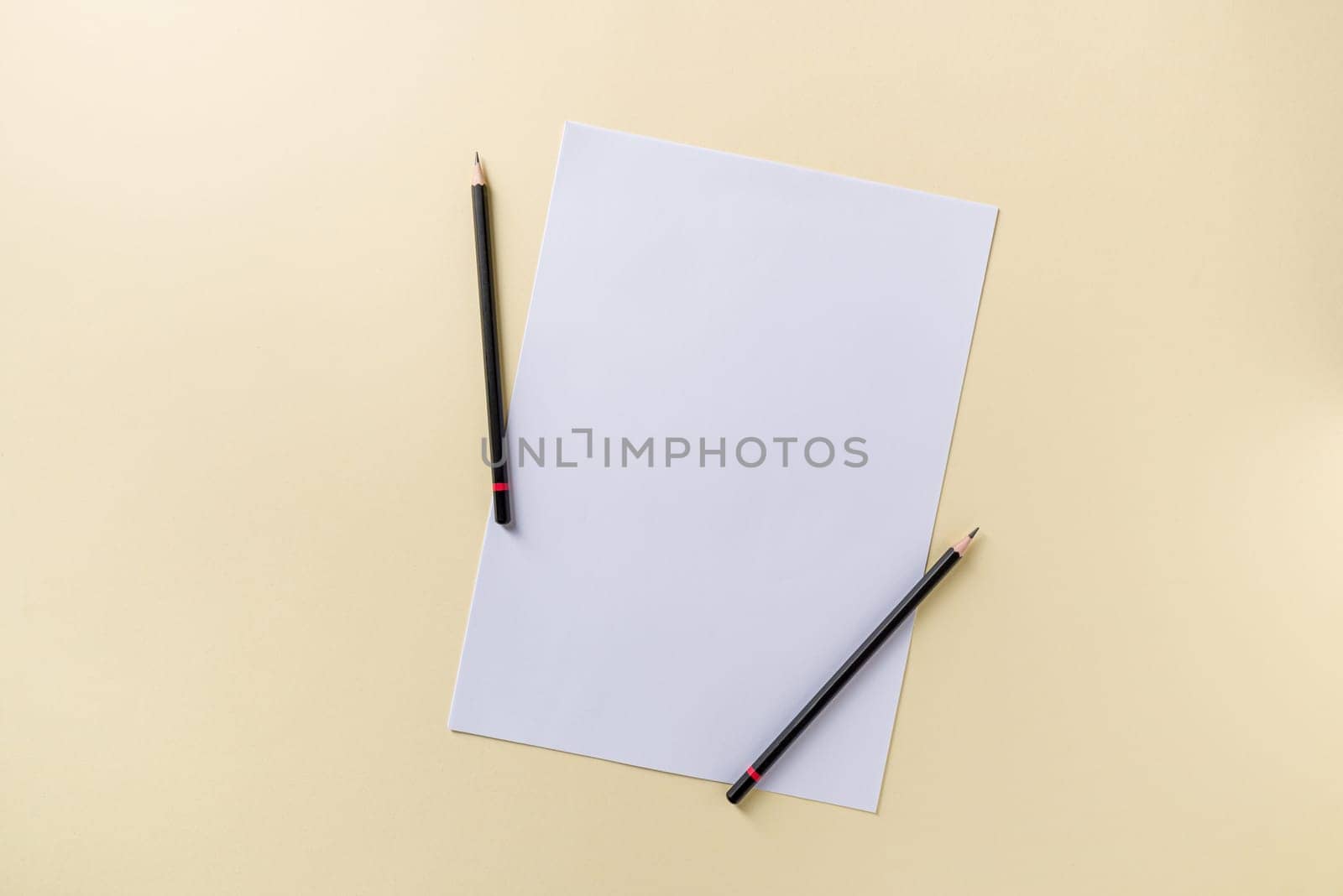 Blank white paper and black pencil on yellow background