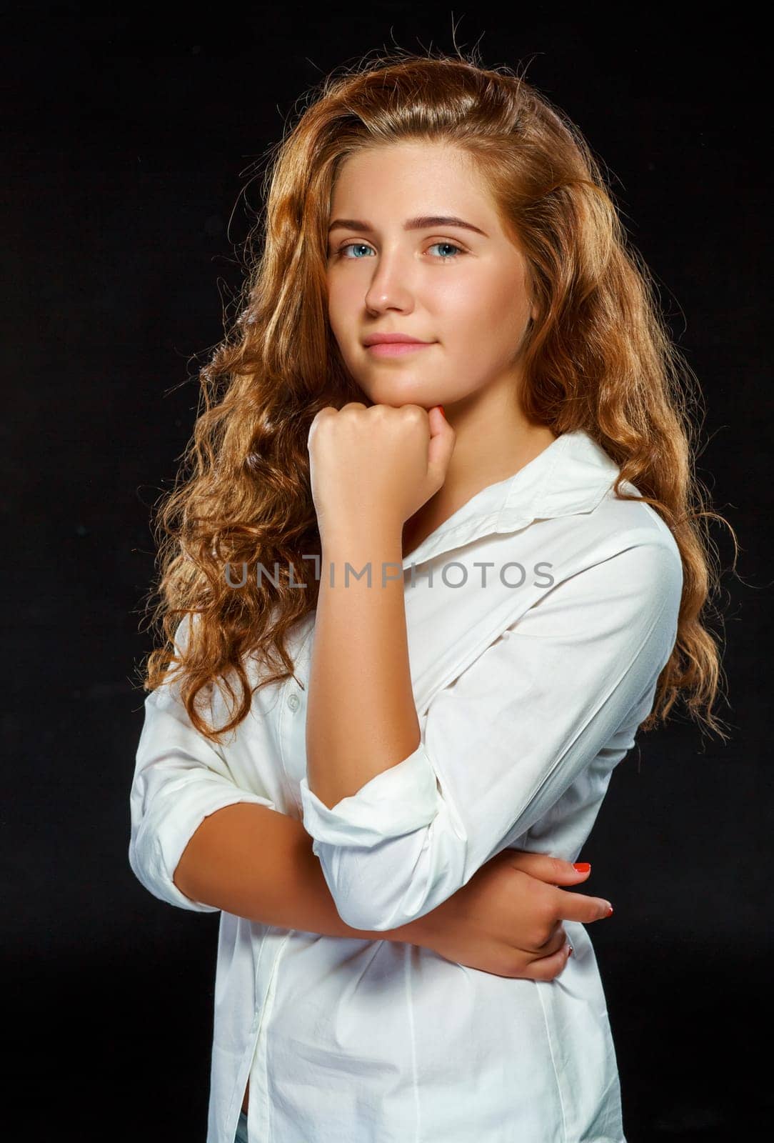 Portrait beautiful young brunette woman with wavy hair in white clothes, looking at the camera, isolated on dark background