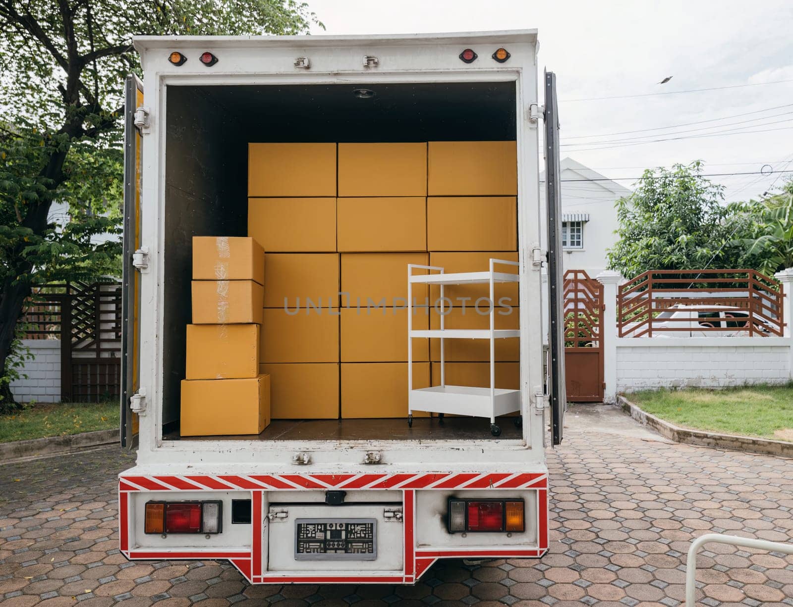 Logistic service outdoors, Open car trunk carrying moving cardboard boxes. White delivery van for house relocation. Transporting items scene. Moving Day Concept.