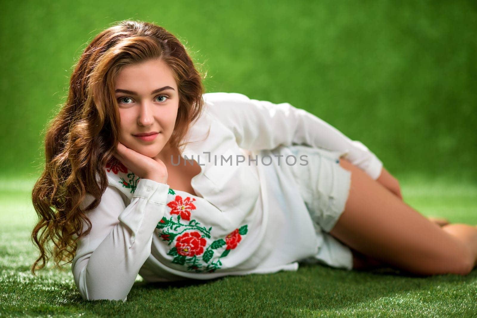 Portrait of pretty smiling young woman, laying on the grass, natural make up long brunette hairs, joy, happiness